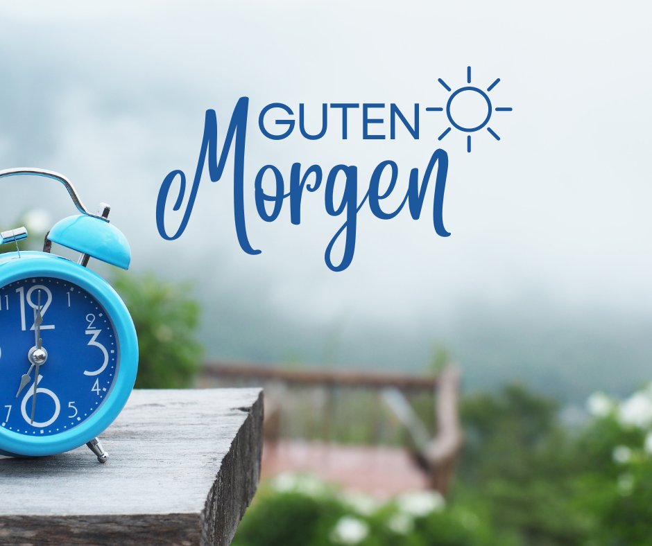Ein inspirierendes Bild für einen schönen guten Morgen mit einem blauen Wecker vor einer nebligen Landschaft, perfekt, um den Tag zu beginnen.